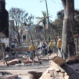 Firefighters sift debris at a property destroyed in the Eaton Fire.