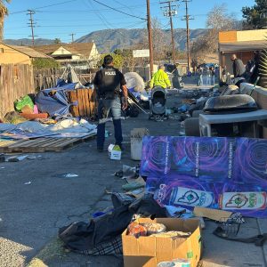 A San Bernardino police officer and city workers remove an encampment Jan. 8 in an alley near Baseline Street.