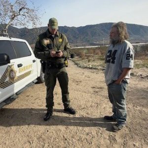 A San Bernardino County sheriff's deputy speaks with a man during a homeless outreach operation Jan. 31 in the San Bernardino area.