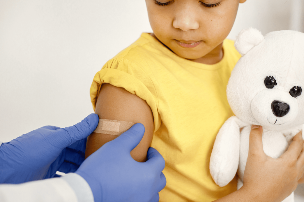 A child's arm receives a post-vaccination band-aid.