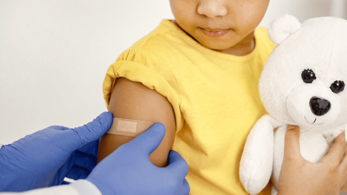 A child's arm receives a post-vaccination band-aid.