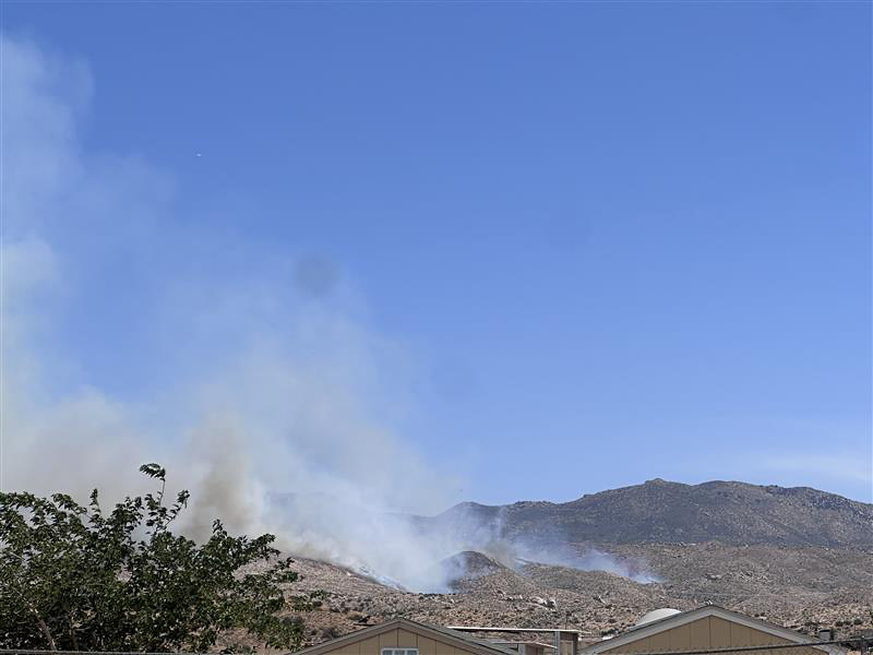 Smoke from the Ranch Fire rises from the hills behind homes in San Bernardino County.