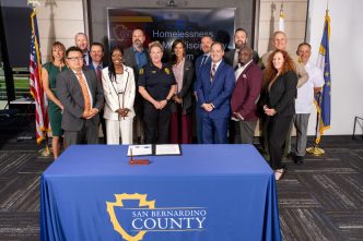County officials gather to sign an agreement to reduce restrictions on sharing homelessness data among departments.