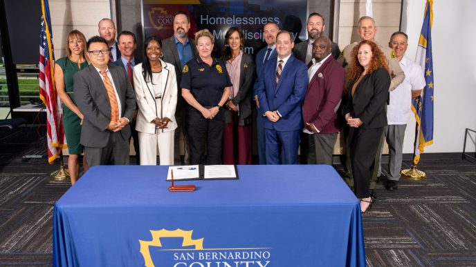 County officials gather to sign an agreement to reduce restrictions on sharing homelessness data among departments.