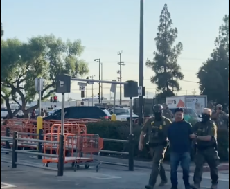 Masked immigration enforcement agents take a man into custody at a Home Depot store in Van Nuys on Saturday, Aug. 8, 2025.