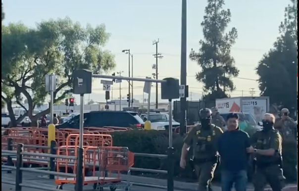 Masked immigration enforcement agents take a man into custody at a Home Depot store in Van Nuys on Saturday, Aug. 8, 2025.