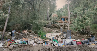 Residents clear debris from a property affected be recent mudslides.