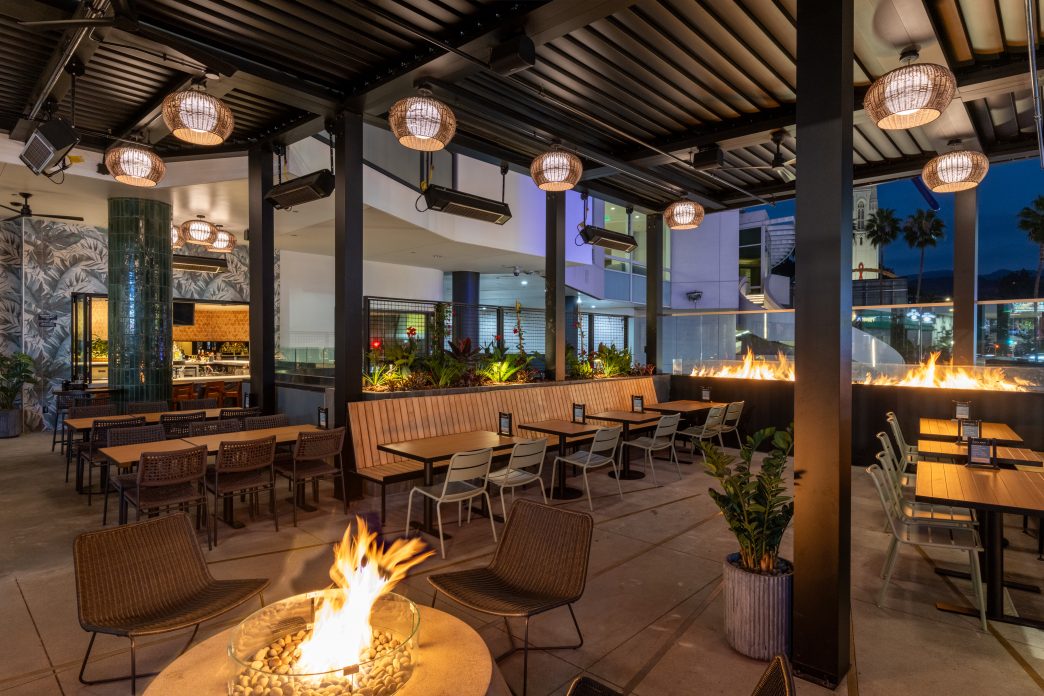 Photo of an outdoor patio with a fire pit and view out to the Hollywood sign at night.