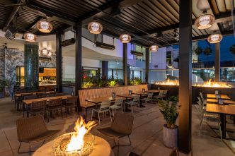 Photo of an outdoor patio with a fire pit and view out to the Hollywood sign at night.