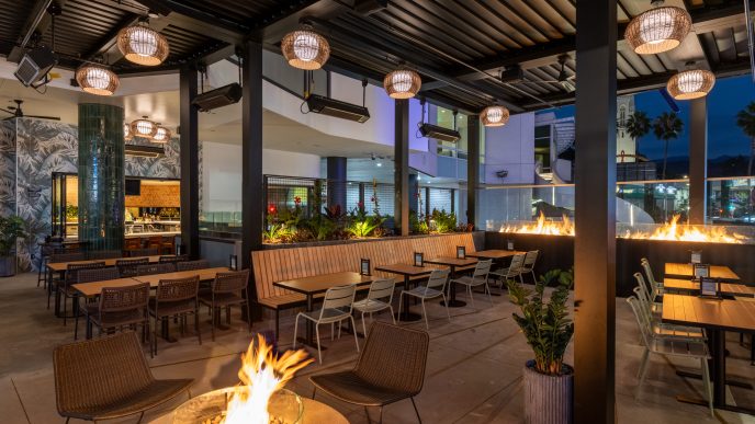 Photo of an outdoor patio with a fire pit and view out to the Hollywood sign at night.