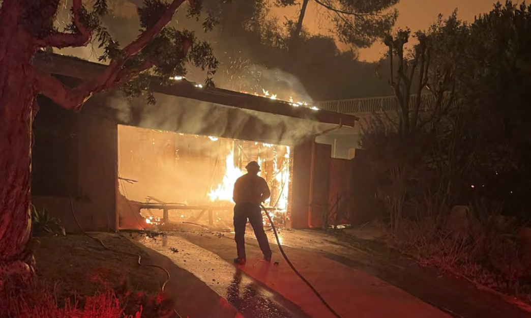 A firefighter battles flames that have engulfed a home during the LA wildfires in January.