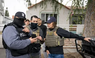 Masked officers brief Department of Homeland Security Secretary Kristi Noem, at right, during an immigration law enforcement operation in Los Angeles June 12, 2025.