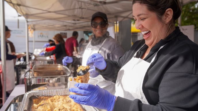 A Union Station Homeless Services volunteer serves mashed potatoes at Dinner in the Park in 2024.