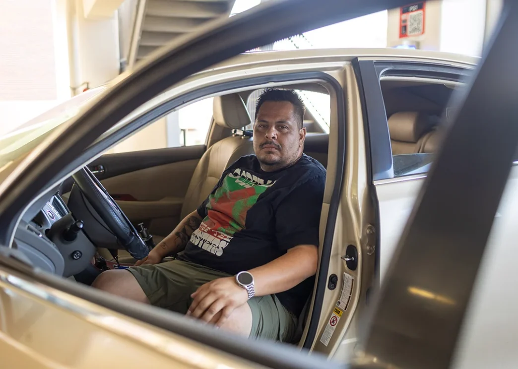 Edgar Rosales Jr., a Long Beach City College student who has experienced homelessness, sits in the car where he lived for three years.