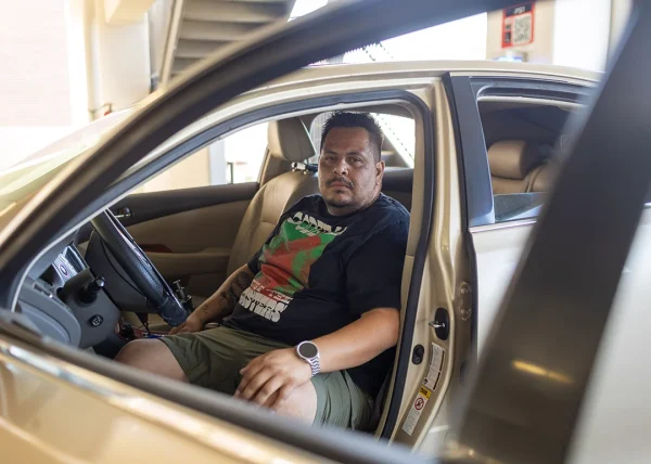 Edgar Rosales Jr., a Long Beach City College student who has experienced homelessness, sits in the car where he lived for three years.