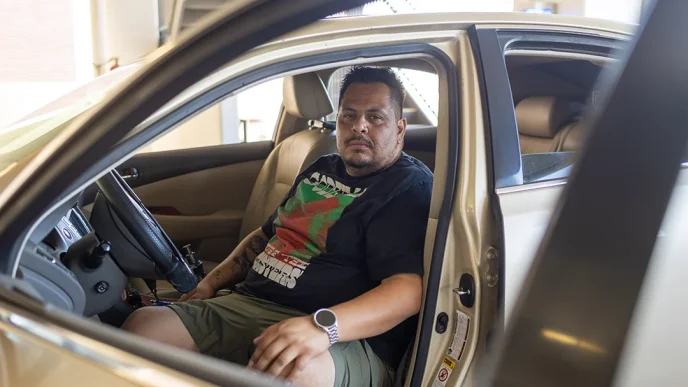 Edgar Rosales Jr., a Long Beach City College student who has experienced homelessness, sits in the car where he lived for three years.