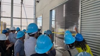 People on a 2024 tour of the direct air capture facility in Tracy examine trays of limestone designed to react with atmospheric carbon dioxide.
