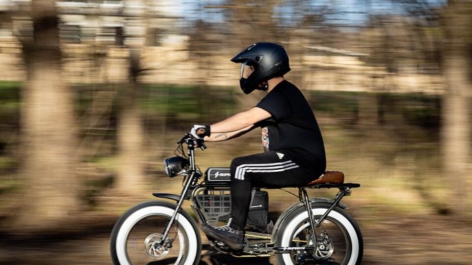 A man wearing a masked helmet riding an electric bike.