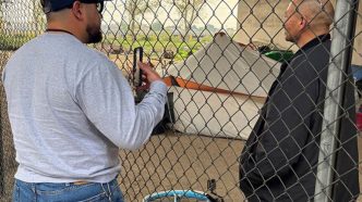 An outreach worker speaks with a man living in a San Bernardino encampment.