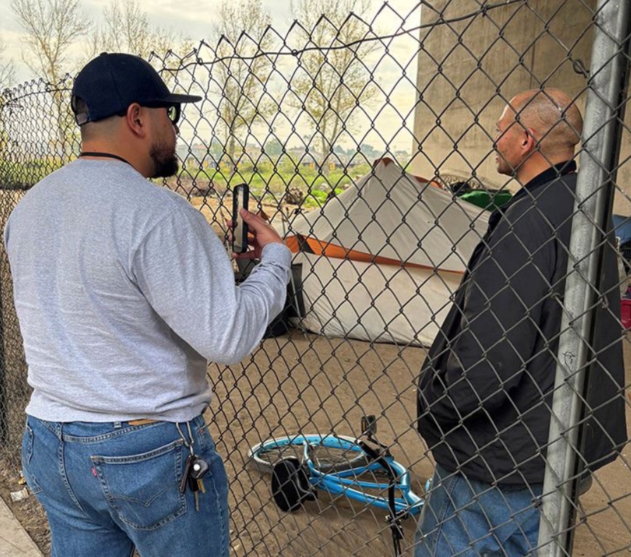 An outreach worker speaks with a man living in a San Bernardino encampment.