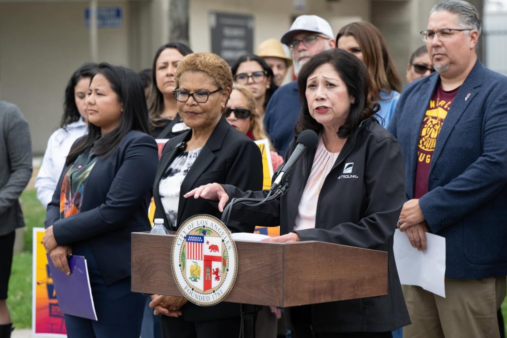 Community members led by LA County Supervisor Hilda Solis, at podium, along with Los Angeles Mayor Karen Bass and City Councilwoman Ysabel Jurado, front row, call for Lineage Logistics to pay for recovery efforts following a large warehouse fire in Boyle Heights.