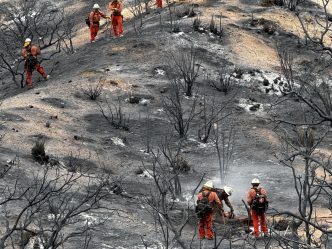Firefighters traverse a smoldering hill near Llano.