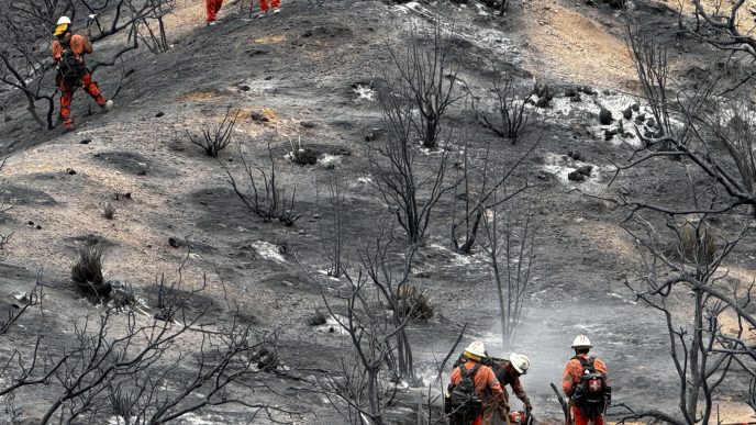 Firefighters traverse a smoldering hill near Llano.