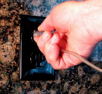 Plugging an appliance into an electrical outlet.