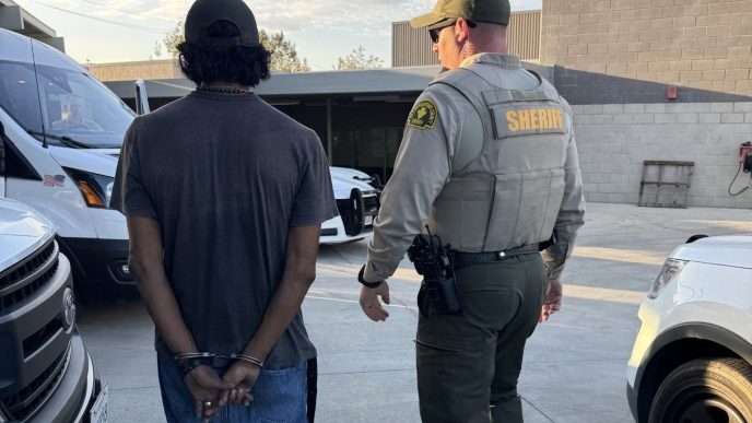 A deputy takes into custody one of the 25 individuals arrested during Operation Shelter Me Aug. 21, 2026, in Rancho Cucamonga.