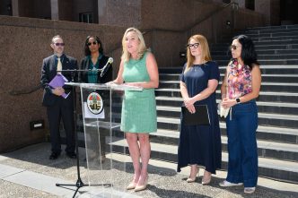 District 5 Supervisor Kathryn Barger announces a lawsuit against State Farm. From left, Assistant County Counsel Scott Kuhn, County Counsel Dawyn Harrison, Barger at podium, Supervisor Lindsey Horvath and fire survivor advocate Joy Chen.