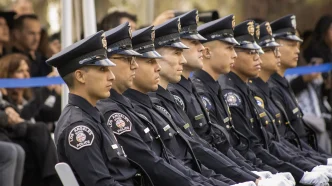 A row of Los Angeles School Police officers in uniform sit together during an outdoor ceremony.