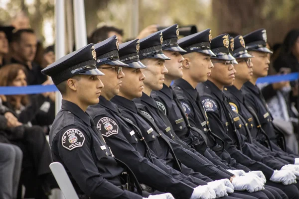 A row of Los Angeles School Police officers in uniform sit together during an outdoor ceremony.