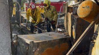 Firefighters go through a destroyed home Saturday during the Norte Fire.